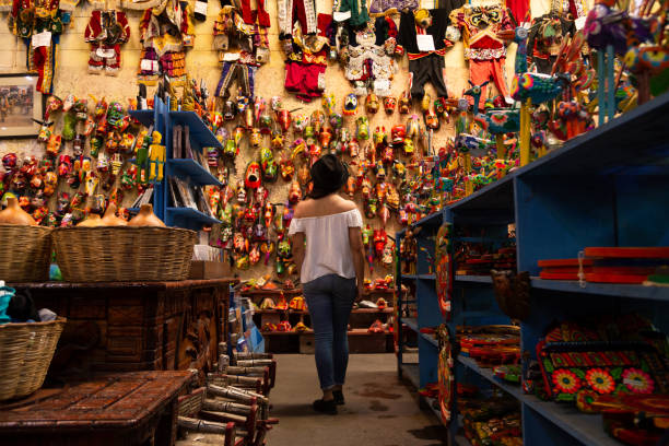手描きの色のマスクでいっぱいの壁の前に立つ若い観光客 - アンティグアグアテマラの手工芸品市場 - 西グアテマラ アンティグア ストックフォトと画像