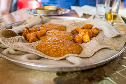 Various vegan curries and dishes served on injera (Ethiopian sourdough flatbread). The platter is known as yetsom beyaynetu and is eaten during religious fasting days.