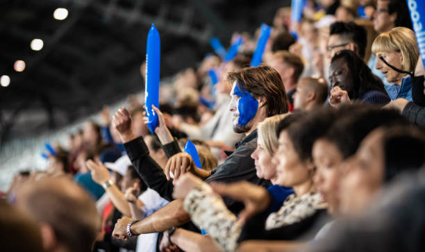 istock Cheering Fans With Blue Banging Thundersticks 1191709916