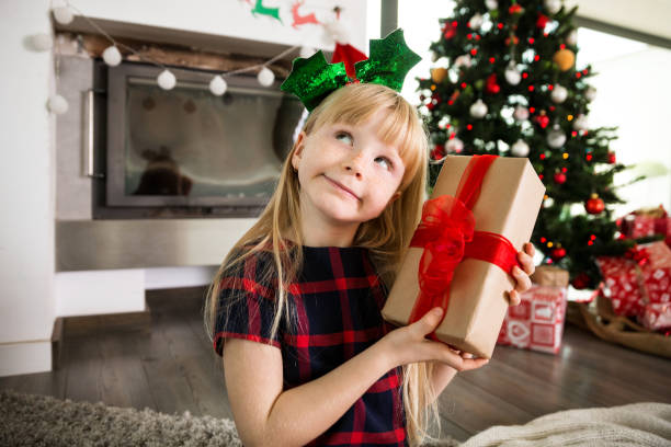 istock Young girl holding christmas gift looking away thinking 1191711405
