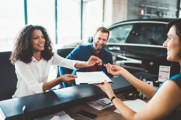 pareja en la sala de exposición comprando coche nuevo - alquiler de coche fotografías e imágenes de stock