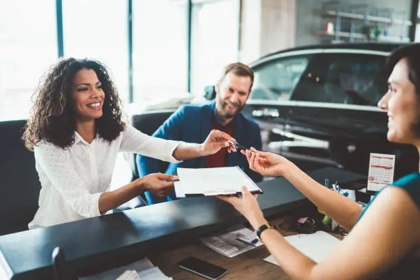 Young woman with her husband signing contract for buying a car