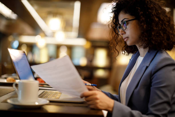 Businesswoman working on laptop at a cafe Businesswoman working on laptop at a cafe analyzing document stock pictures, royalty-free photos & images