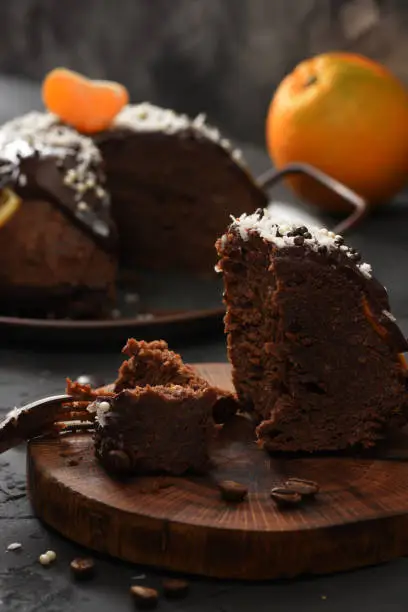 Traditional festive dessert. Steam chocolate pudding with orange and clementine cut on wood slab on black background low key