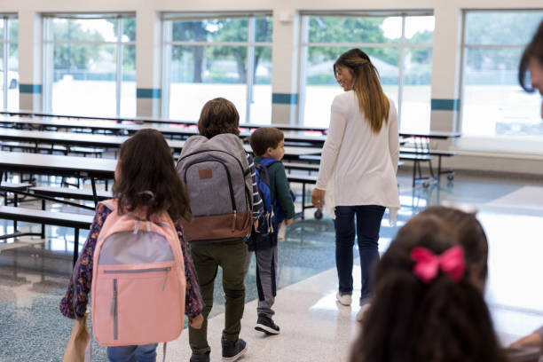 istock Female teacher leads students into school cafeteria 1191725305