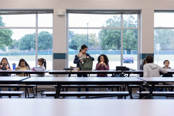 昼食を食べる小学生のグループ - cafeteria ストックフォトと画像