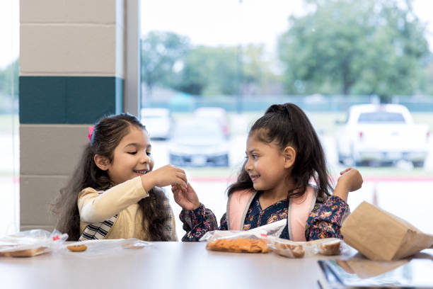 bliźniaczki dzielą obiad w szkolnej stołówce - school lunch zdjęcia i obrazy z banku zdjęć