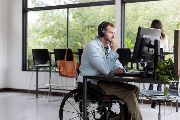 istock Man in wheelchair working in IT support 1191725548