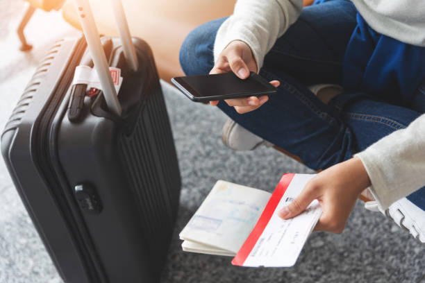 Asian woman traveler is sitting and using smartphone at the airport. Asian woman traveler is sitting and using smartphone at the airport. Holiday and Vacation. airplane ticket photos stock pictures, royalty-free photos & images