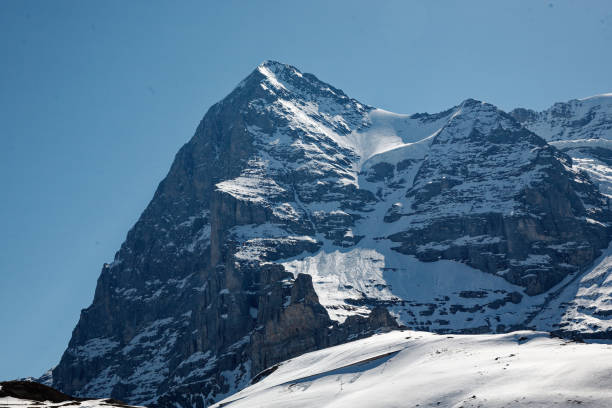 North Face of the Eiger Switzerland North face of the Eiger mountain range with snow and rock face. Blue sky. No people. Snow slopes to foreground. eiger northface stock pictures, royalty-free photos & images