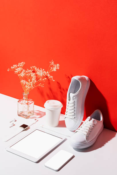 Accessories and digital tablet organised neatly on red and white background