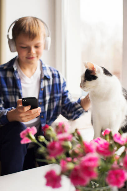 istock Young boy and cat sitting by the window 1191734131