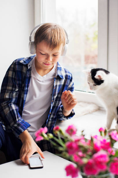 istock Young boy and cat sitting by the window 1191734176