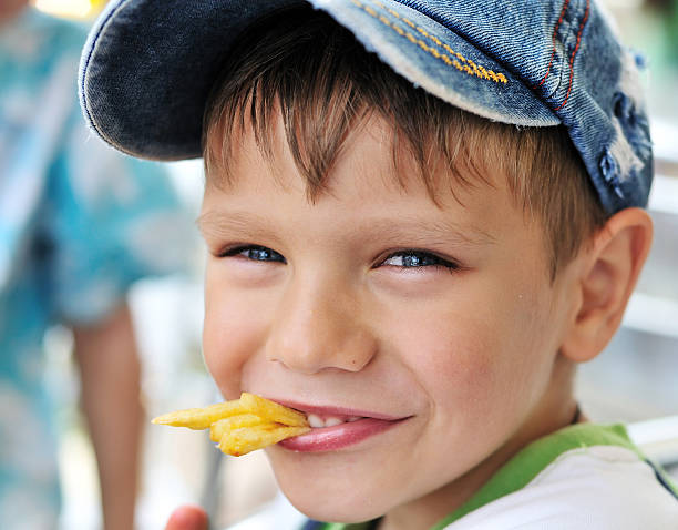 Caucasian beautiful little girl looking at the camera smiling eating macaroni and cheese