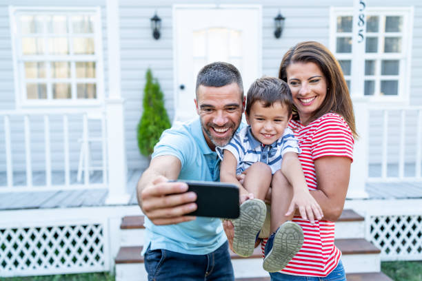 istock Parents with child having fun in front yard and taking selfie 1191735402