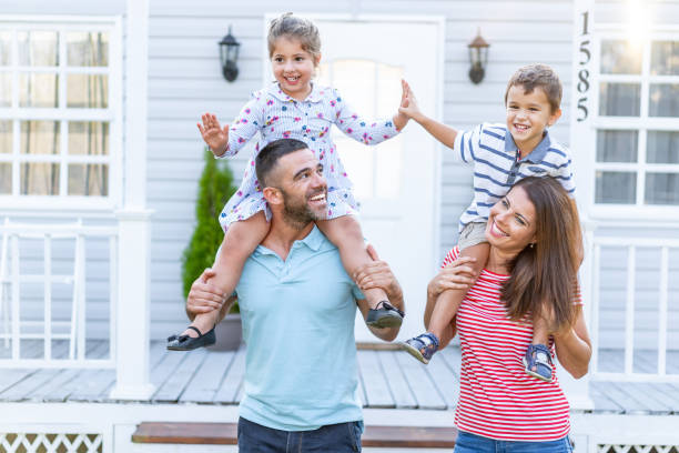 istock Parents having fun in front yard carrying children piggyback 1191735403