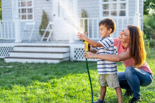 istock Mother splashing water and having fun with son on back yard 1191735408