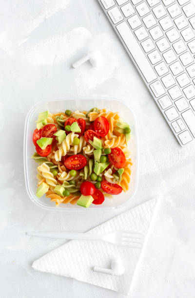 istock Italian pasta with vegetables on office desk with keyboard 1191736219