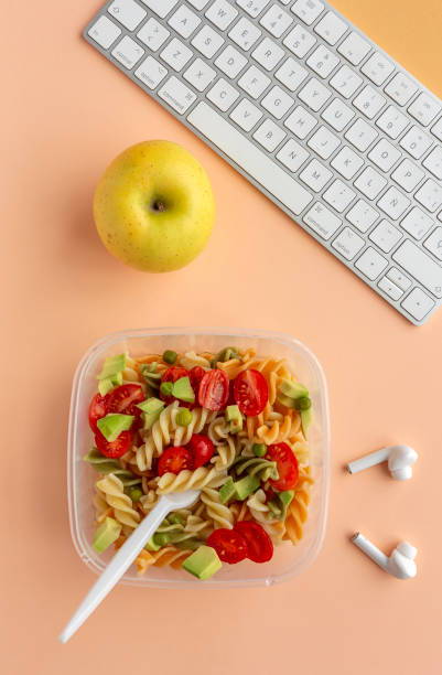 istock Italian pasta with vegetables on office desk with keyboard 1191736232