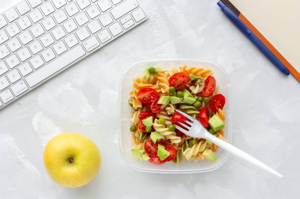 istock Italian pasta with vegetables on office desk with keyboard 1191736238