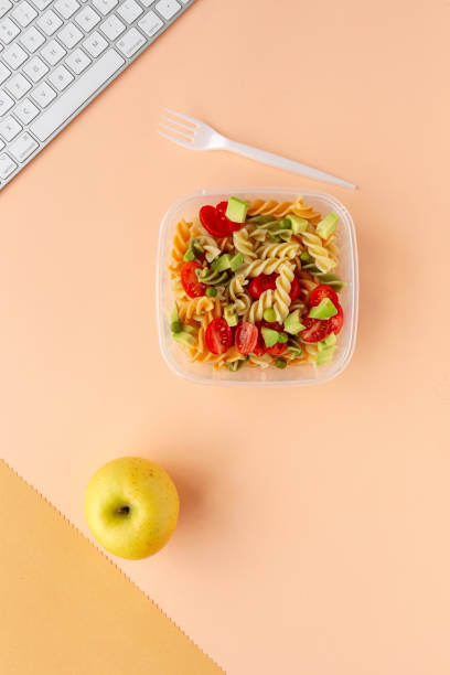 istock Italian pasta with vegetables on office desk with keyboard 1191736280