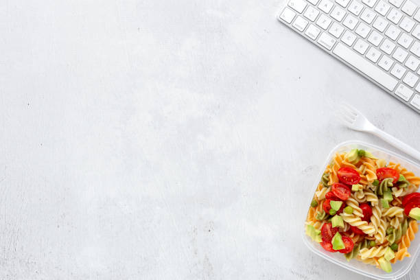 istock Italian pasta with vegetables on office desk with keyboard 1191736298
