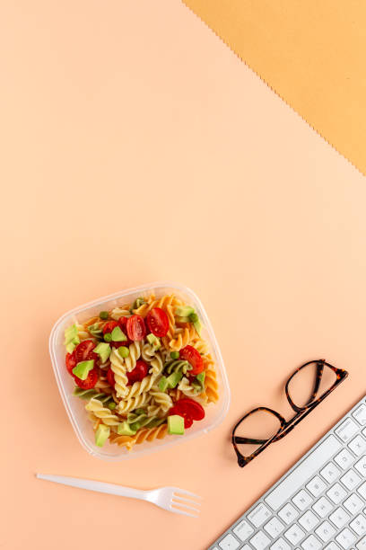 istock Italian pasta with vegetables on office desk with keyboard 1191736301