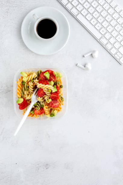 istock Italian pasta with vegetables on office desk with keyboard 1191736320