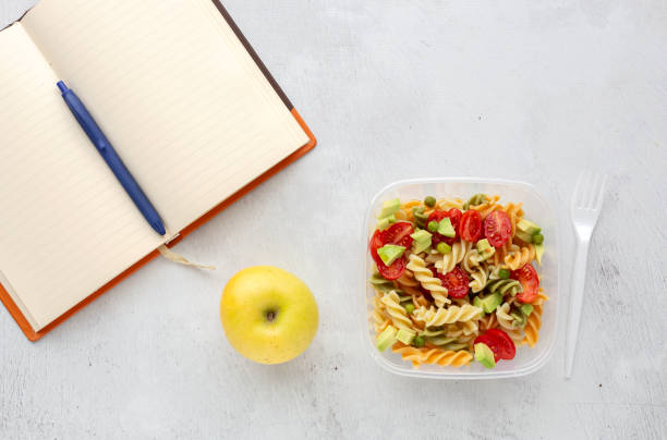 istock Italian pasta with vegetables on office desk with keyboard 1191736337