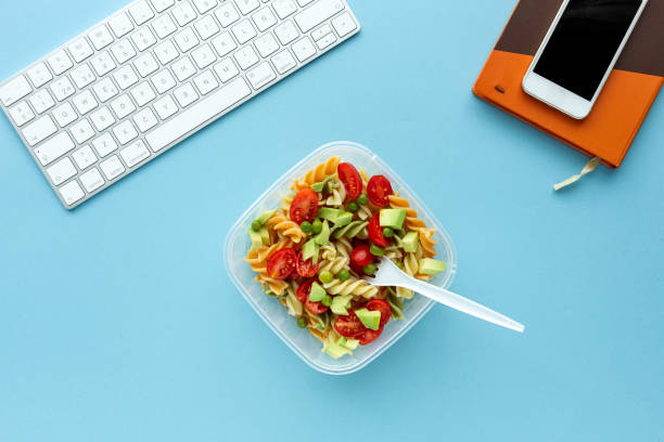 istock Italian pasta with vegetables on office desk with keyboard 1191736343
