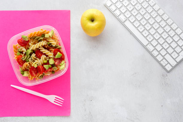 istock Italian pasta with vegetables on office desk with keyboard 1191736346