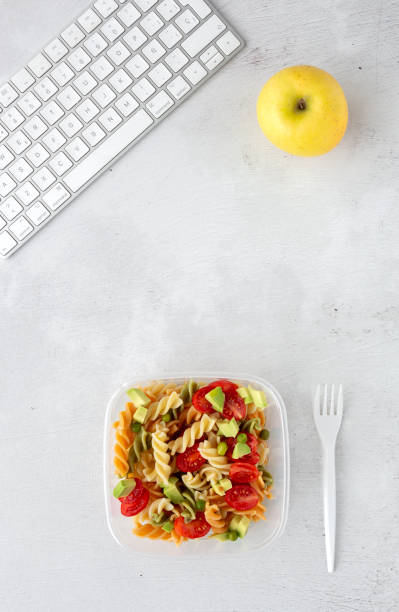 istock Italian pasta with vegetables on office desk with keyboard 1191736349