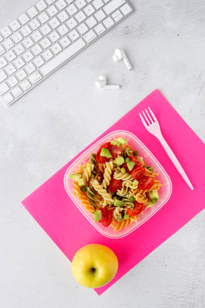 istock Italian pasta with vegetables on office desk with keyboard 1191736351