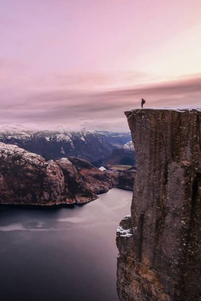 wanderer auf dem berühmten preikestolen über dem lysefjord, schöne farben bei sonnenuntergang, ryfylke, rogaland, norwegen - lysefjord stock-fotos und bilder