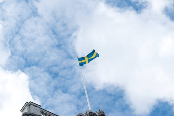istock Flag of Sweden on cloudy sky. 1191739150