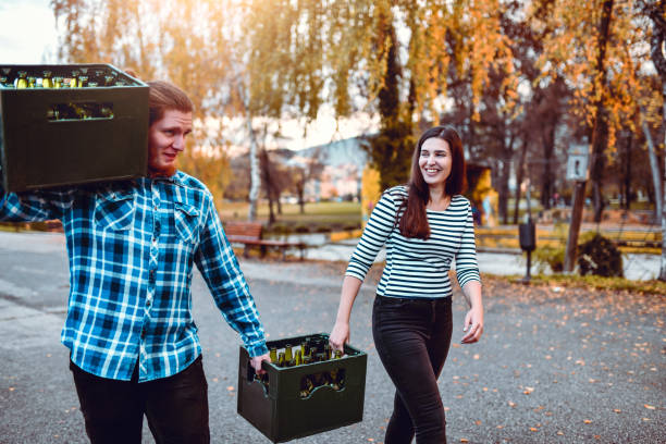 Couple Taking Beer Crates To Park Picnic Party Couple Taking Beer Crates To Park Picnic Party beer crate stock pictures, royalty-free photos & images