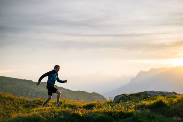 le jeune homme court sur la crête de montagne au lever de soleil - distance running jogging running fog photos et images de collection