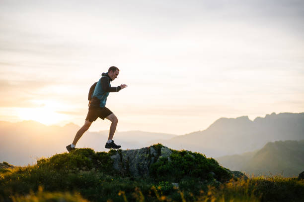 le jeune homme court sur la crête de montagne au lever de soleil - distance running jogging running fog photos et images de collection