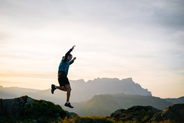 le jeune homme court sur la crête de montagne au lever de soleil - distance running jogging running fog photos et images de collection