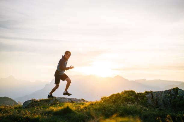 le jeune homme court sur la crête de montagne au lever de soleil - distance running jogging running fog photos et images de collection