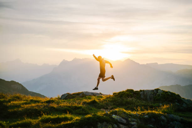 le jeune homme court sur la crête de montagne au lever de soleil - distance running jogging running fog photos et images de collection