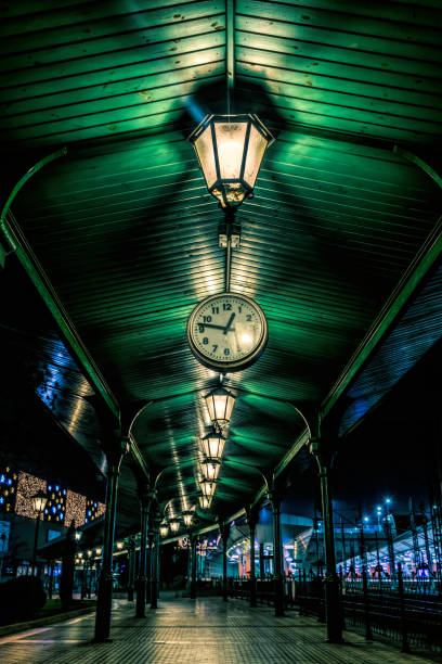 Krakow, Poland - November 29, 2019: Antique clock on a vintage railway platform in the historical center of Krakow, Poland. Shining street lights of an old European city on Christmas Eve
