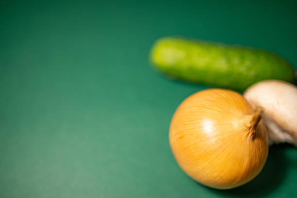 onion, mushroom, cucumber on green background rear view