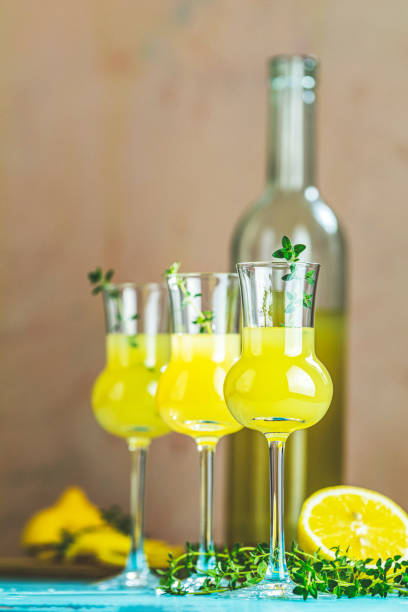 istock Limoncello with thyme in grappas wineglass with water drops on light concrete table. Artistic still life on light background with sunny light. 1191753240