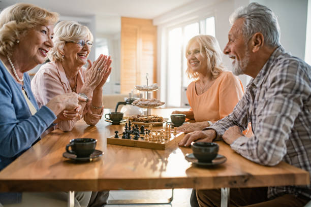 istock Happy mature friends talking while playing chess at home. 1191757306