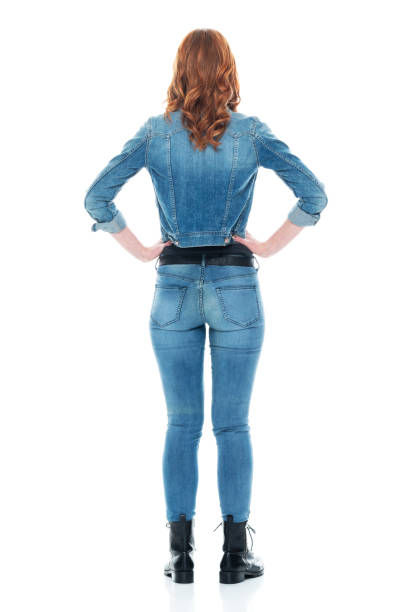 full length / rear view / back / one person of 20-29 years old adult beautiful redhead / long hair caucasian female / young women standing wearing double denim / jeans / pants / denim jacket / boot / rolled-up sleeves / jacket / warm clothing - one young woman only only young women one woman only 20 25 years imagens e fotografias de stock