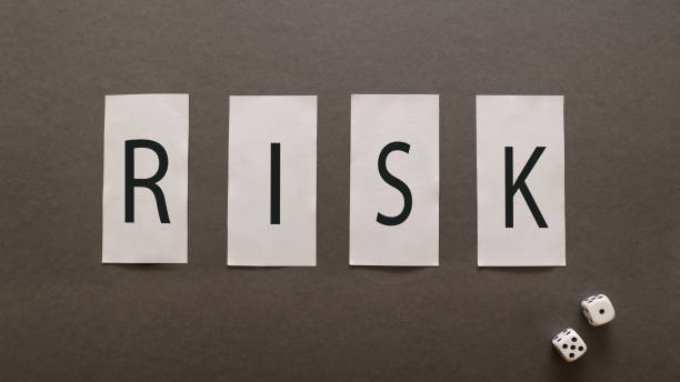 istock RISK inscription on white blocks on a gray background with game cubes. 1191758432
