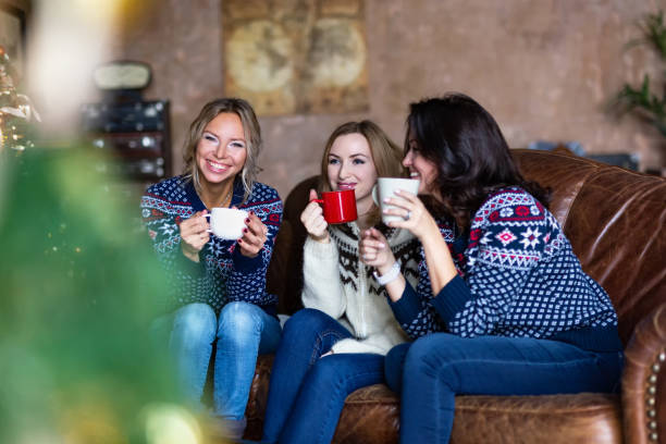 istock Three smiling women talking and drinking coffee while sitting on a couch 1191759924