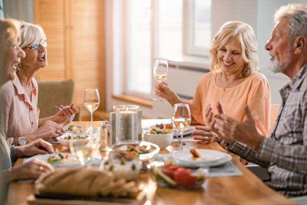 istock Group of happy senior people talking while eating and drinking wine at dining table. 1191762316