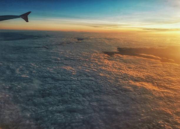 By mobile phone early morning first light from cabin passenger seat window view cloudscape with sunlight